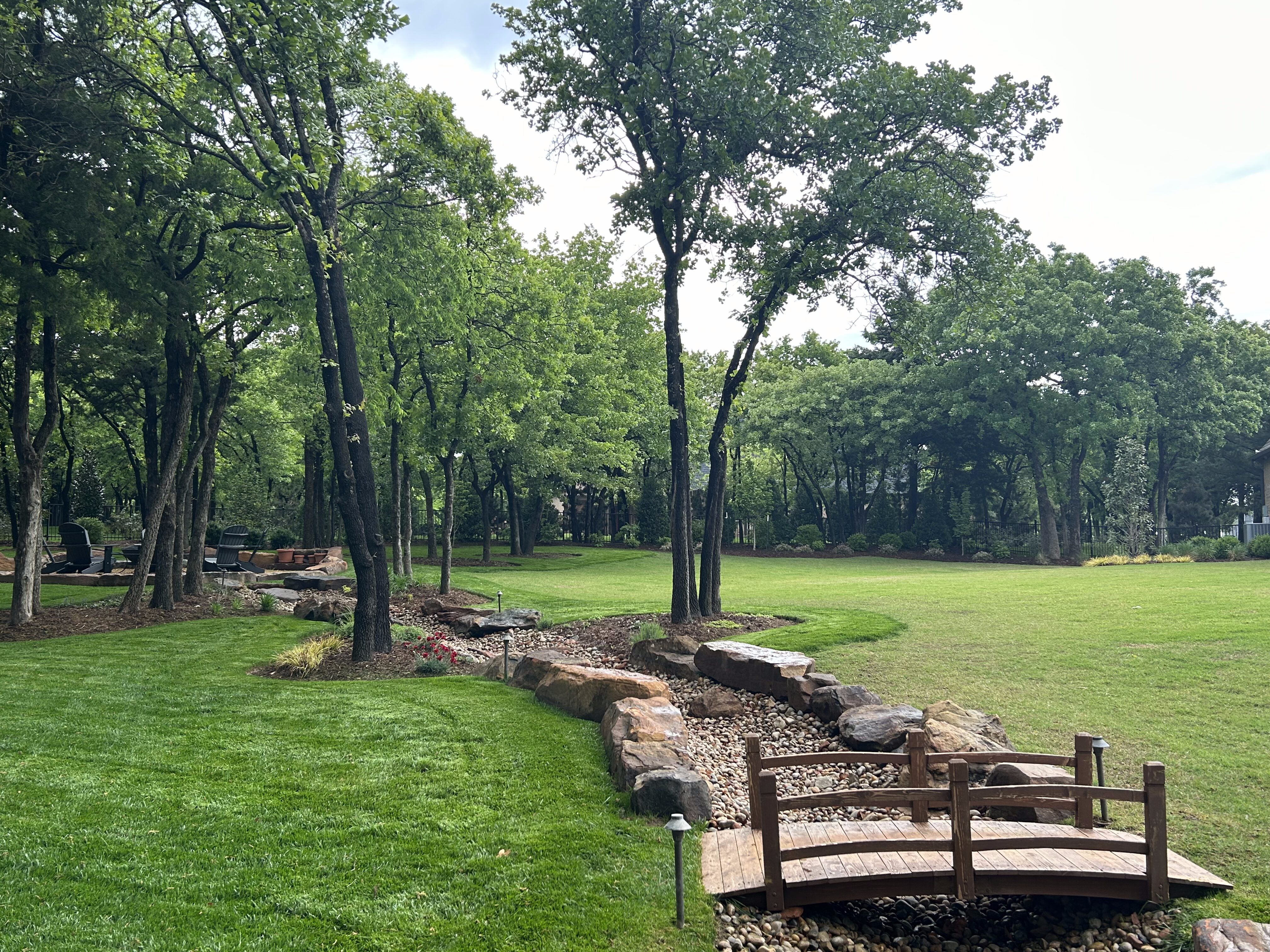 Close-up of tree-filled backyard with creek and bridge