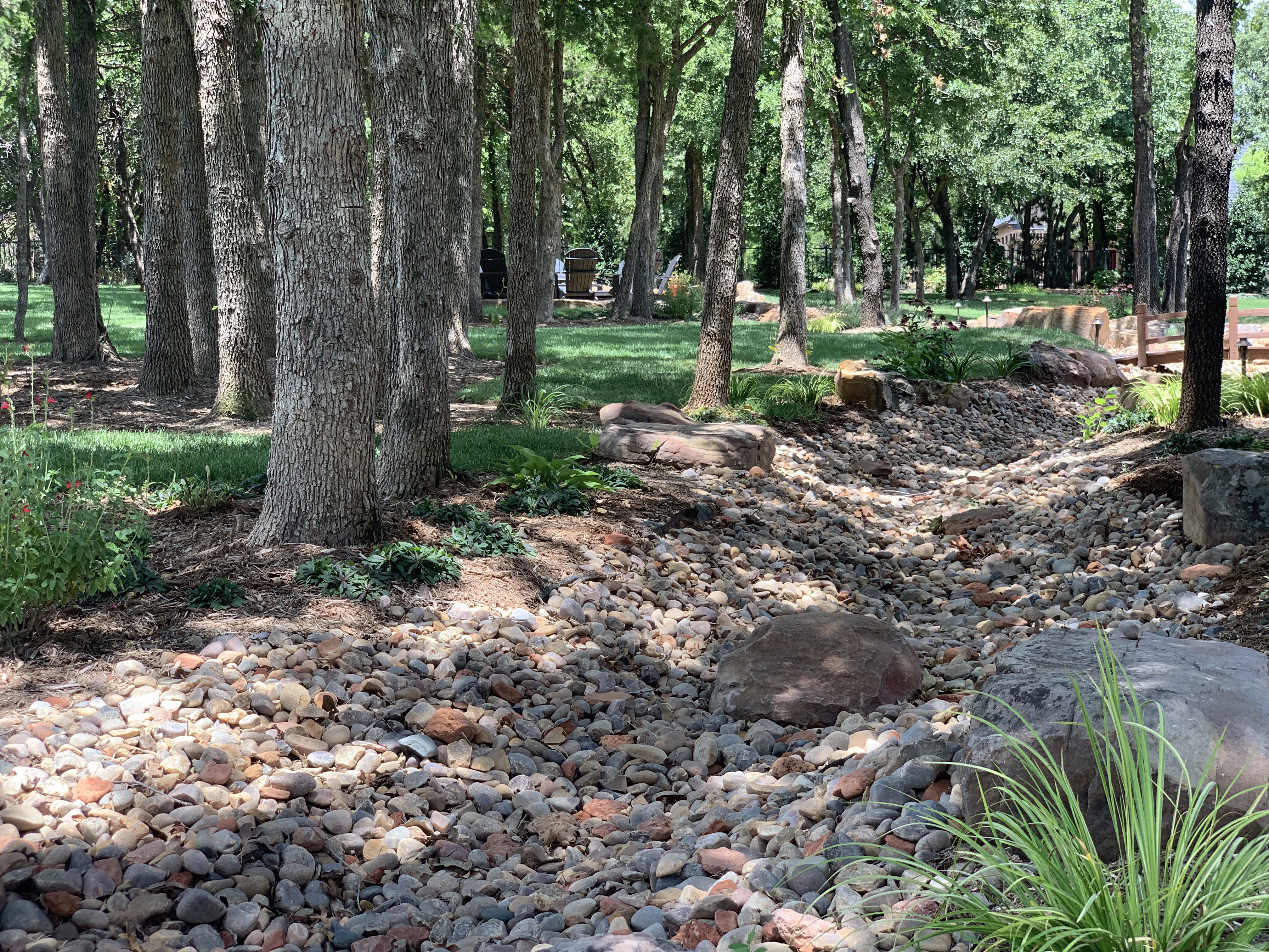 Close-up of tree-filled backyard with creek and bridge