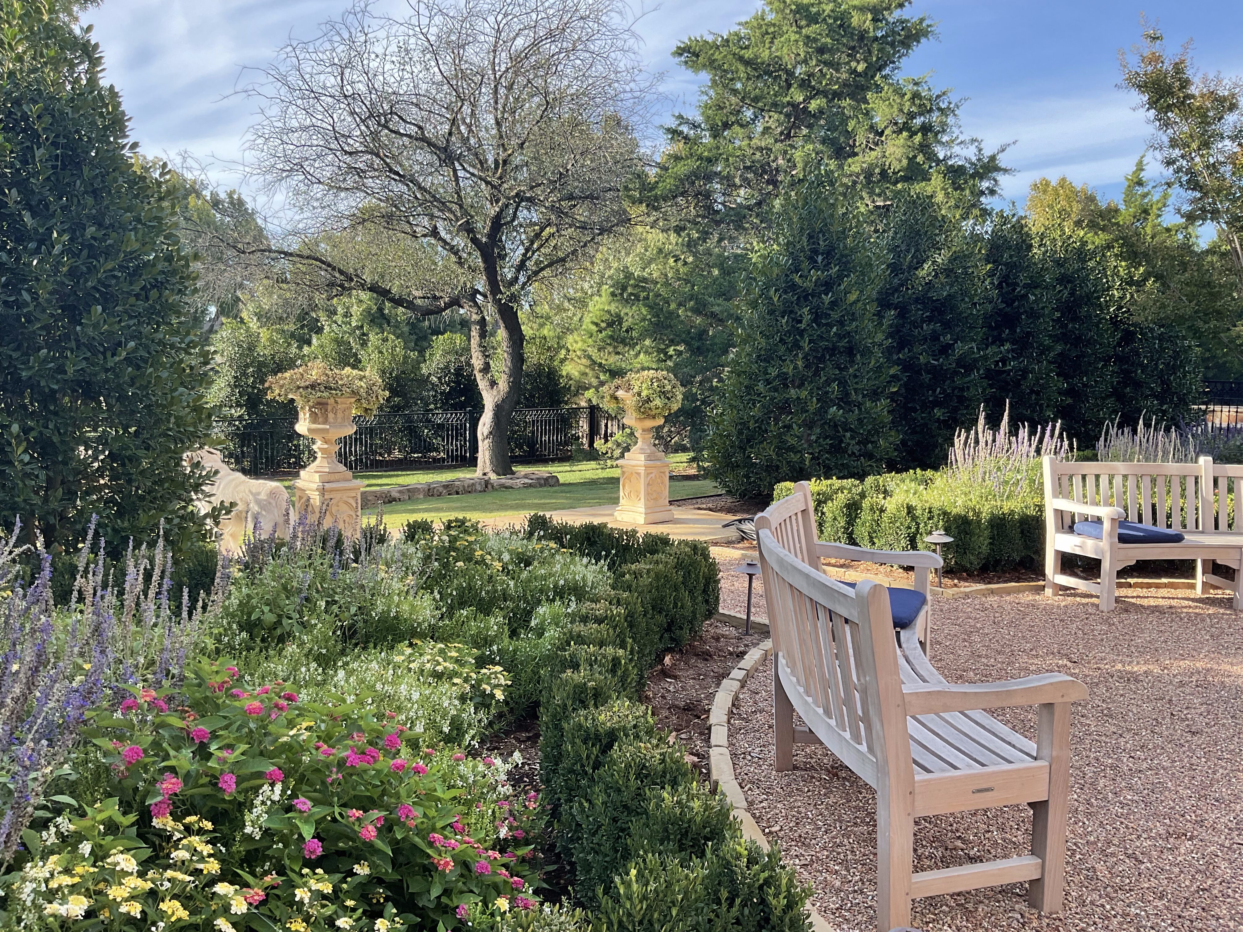 Nichols Hills English garden with gravel seating area and wood benches