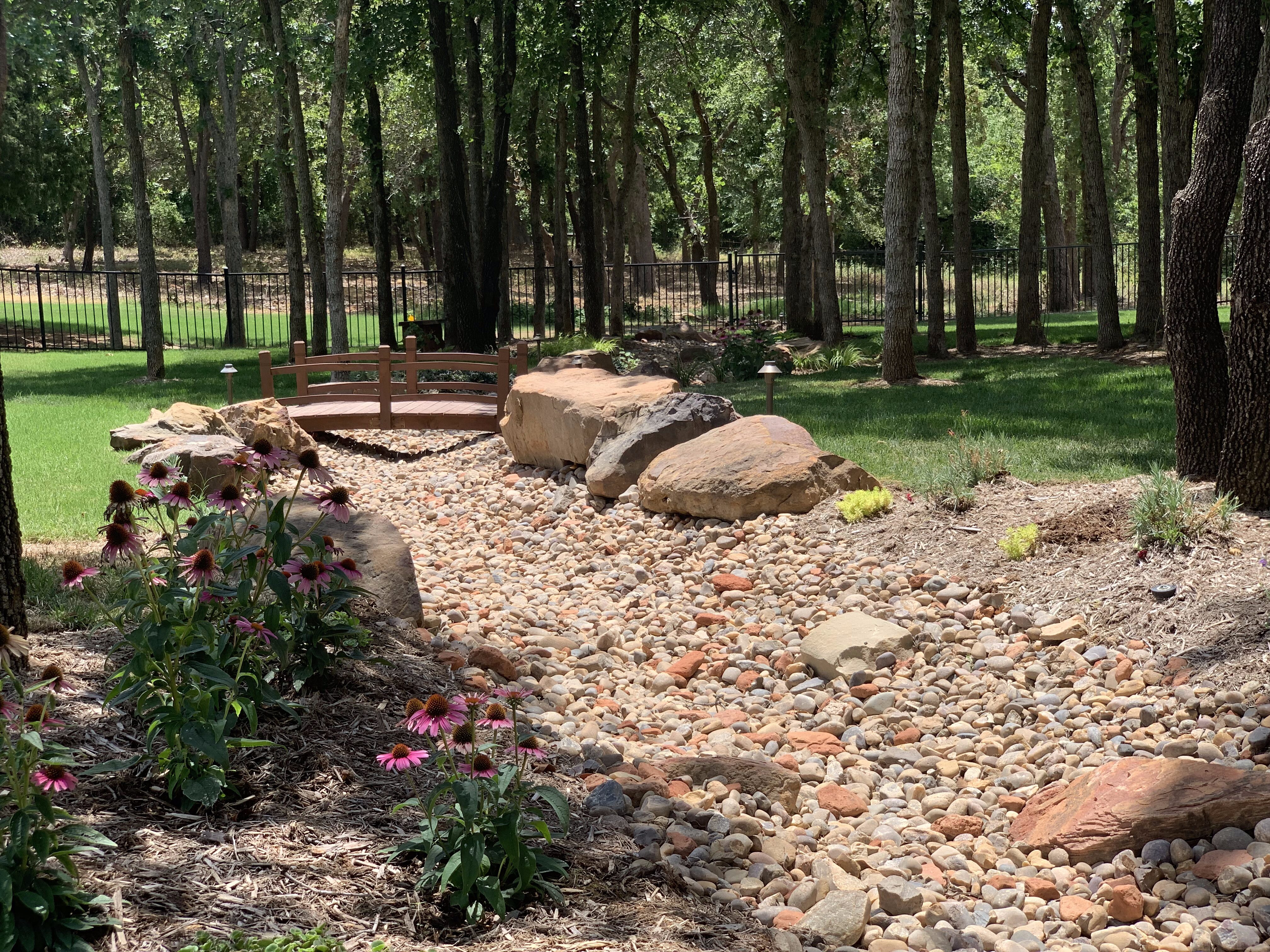 Close-up of tree-filled backyard with creek and bridge