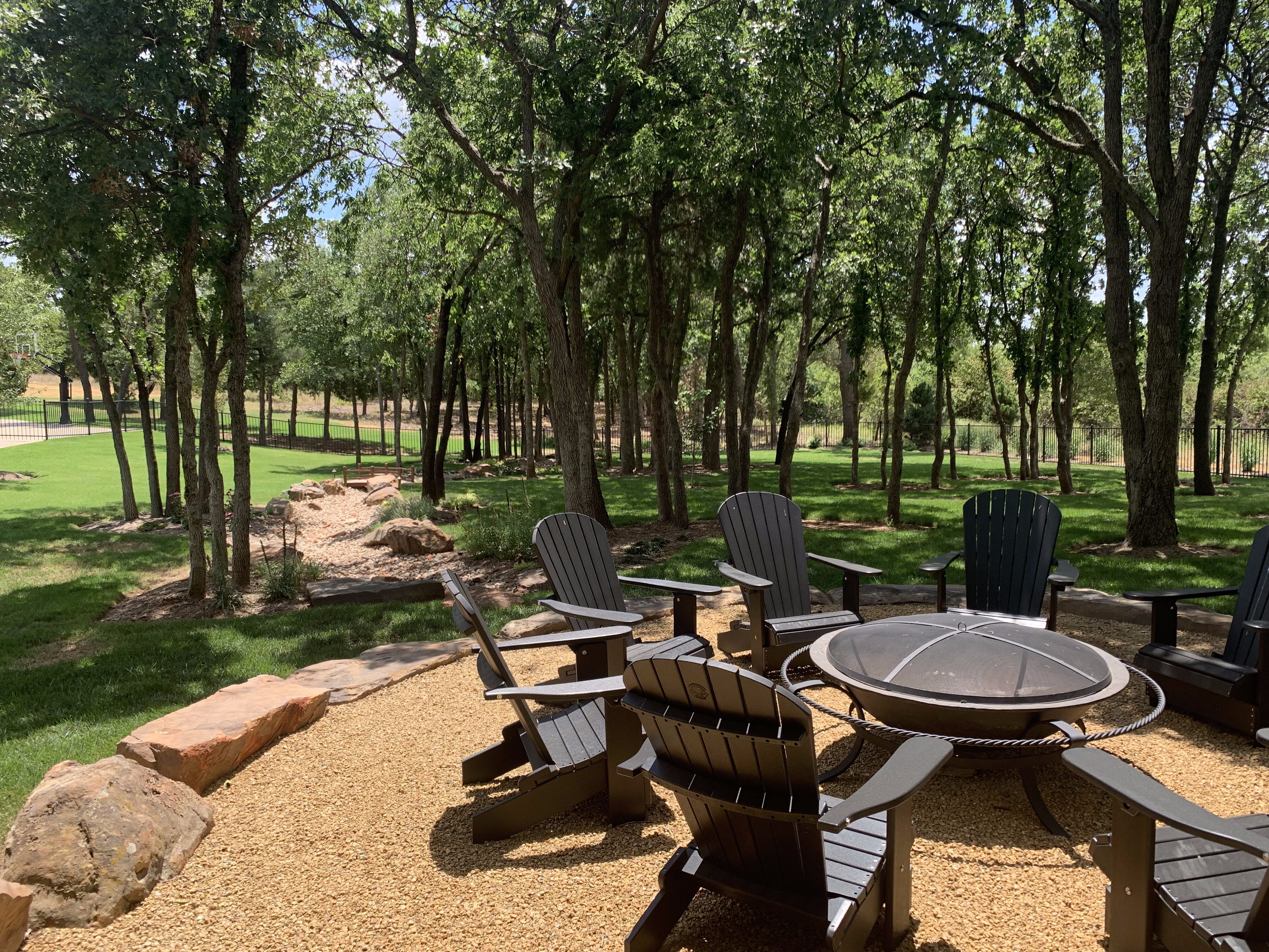 Tree-filled backyard with crushed granite firepit and creek