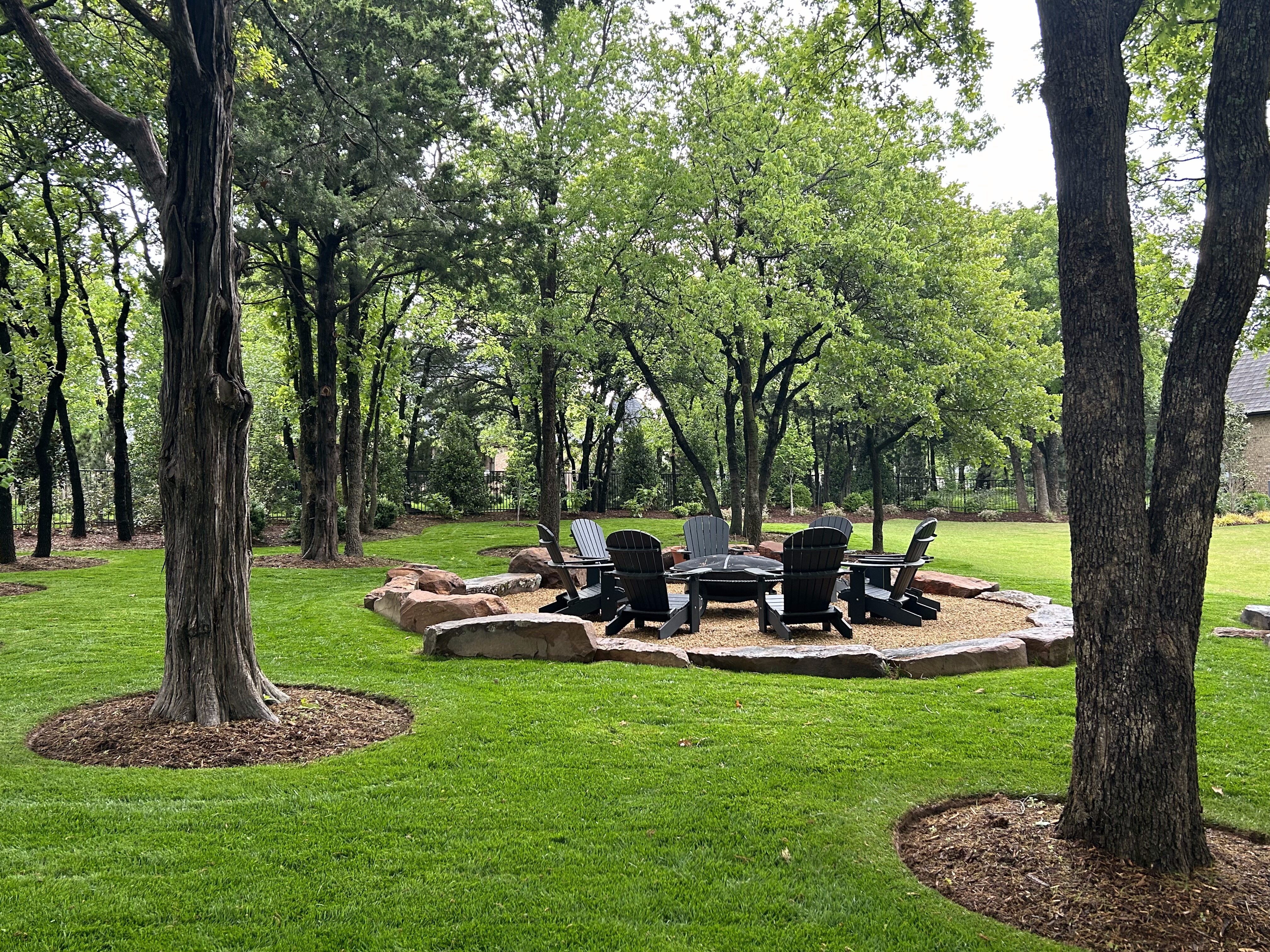 Tree-filled backyard with crushed granite firepit with seating
